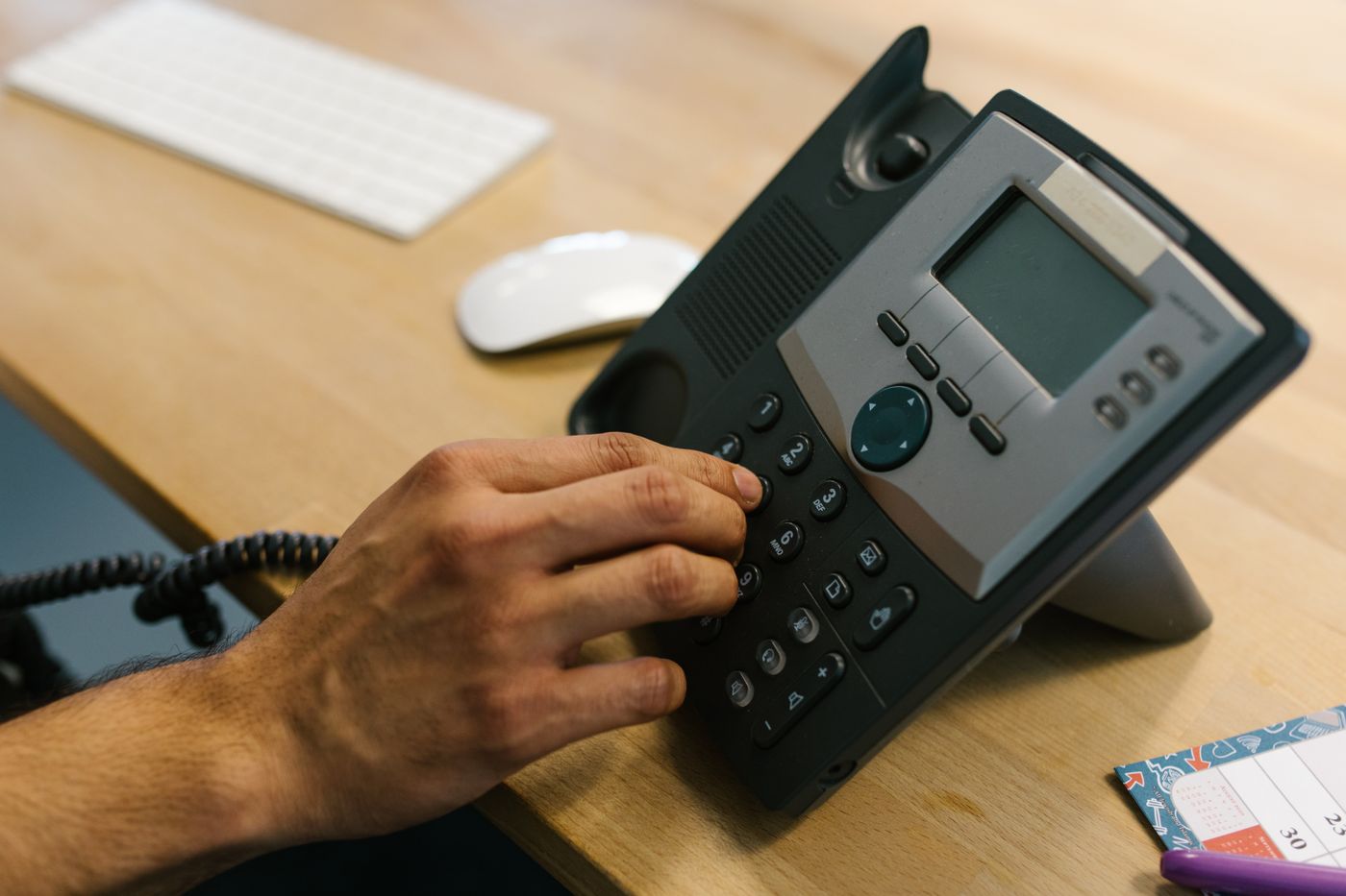 Mão discando em telefone de mesa