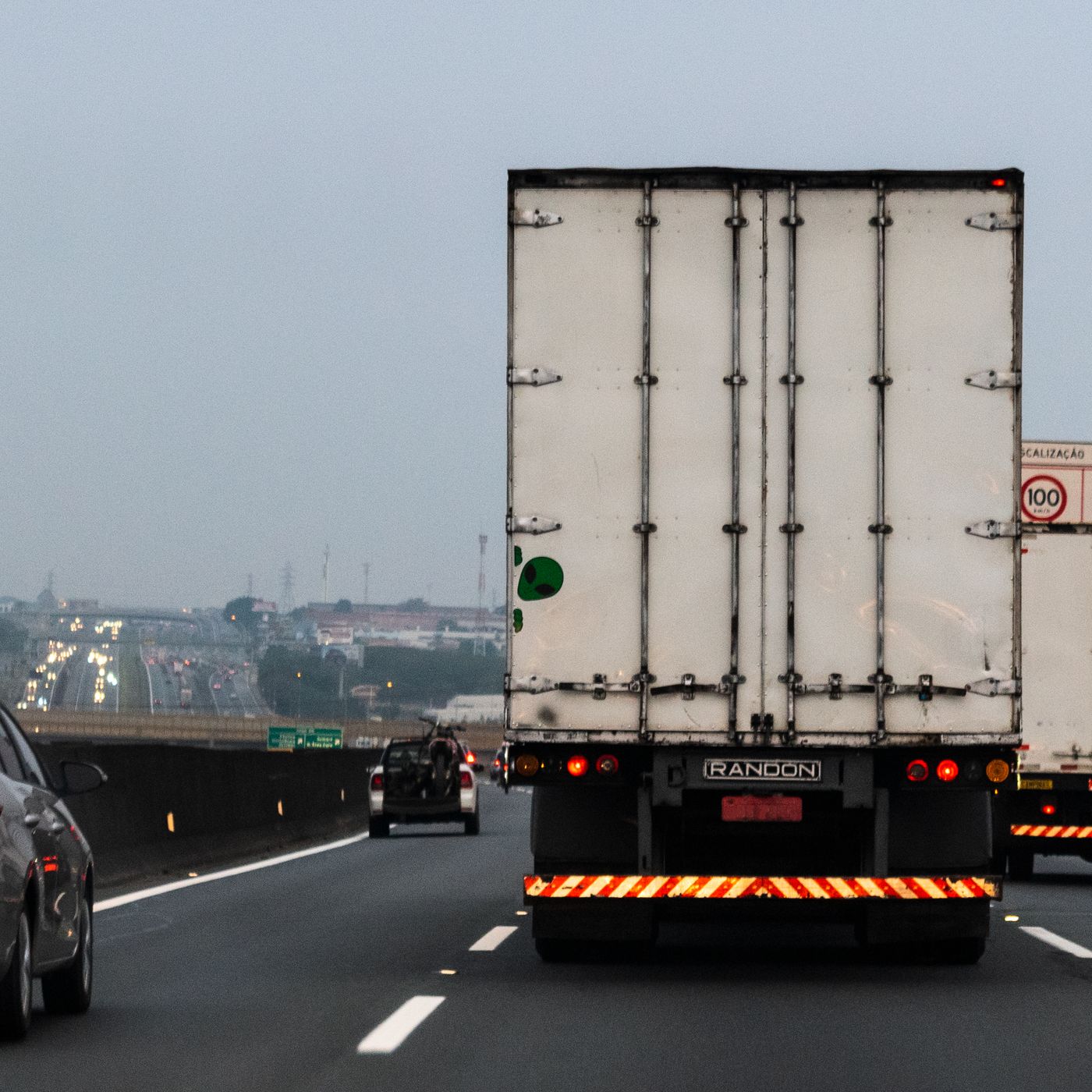 Caminhão baú em rodovia com placa de limite de 100 km/h