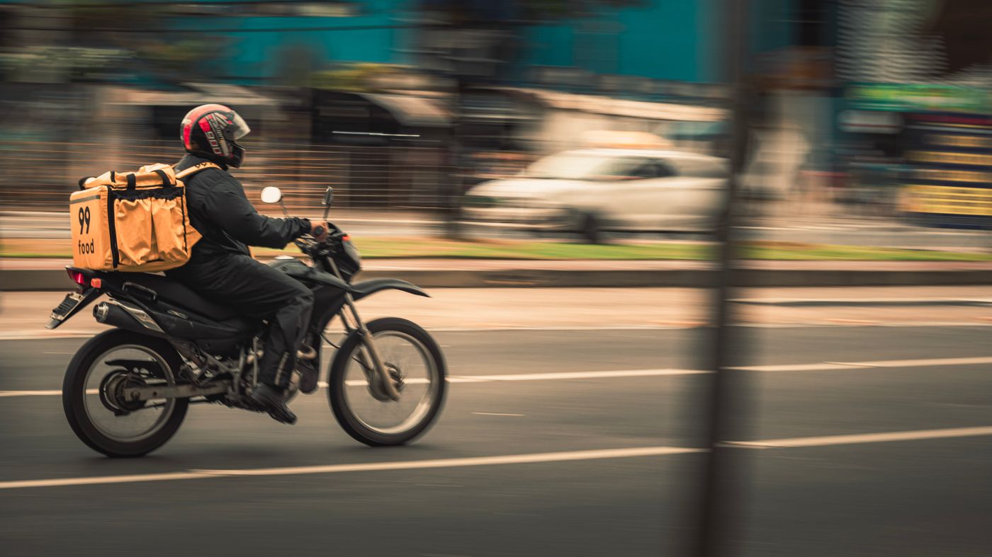 Motoboy com bag de entrega em avenida